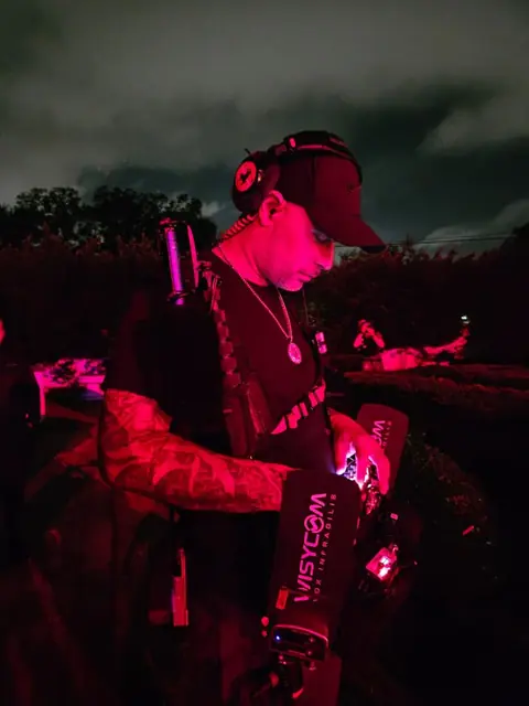 Dre of SoundNinjas mixing from a bag rig on a night exterior